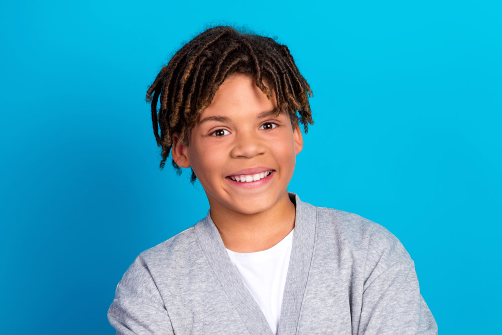 Teen young man smiling on blue background