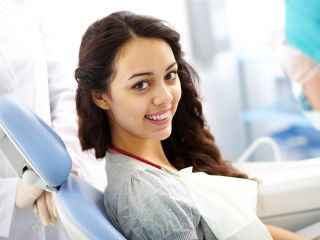 Young woman smiling while at orthodontics appointment | Oral health