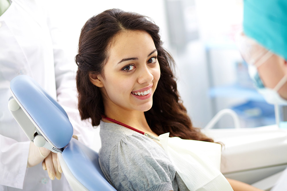 Young woman smiling while at orthodontics appointment | Oral health